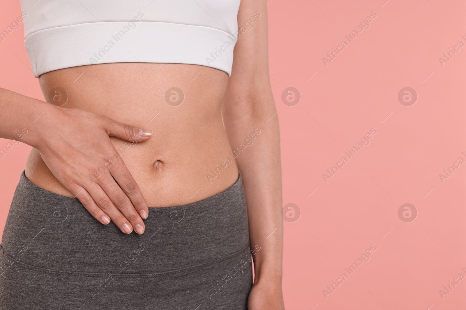 Photo of Healthy digestion. Woman touching her belly on pink background, closeup. Space for text