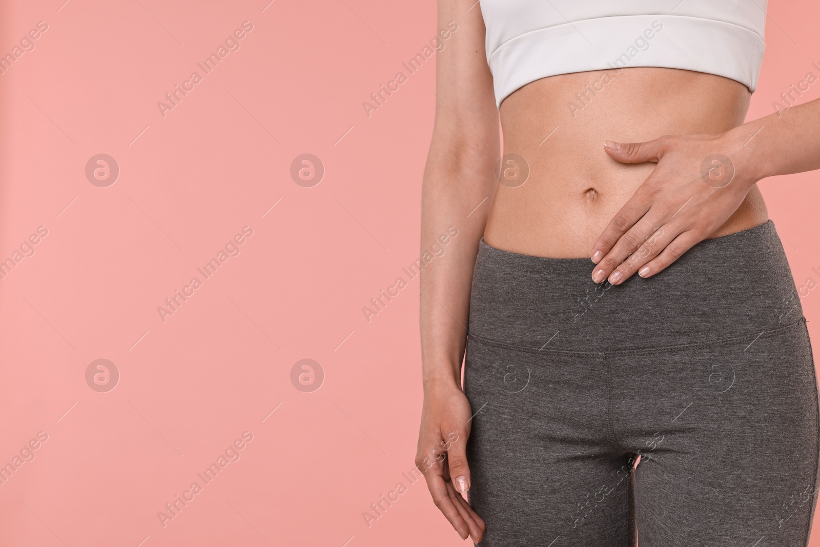 Photo of Healthy digestion. Woman touching her belly on pink background, closeup. Space for text