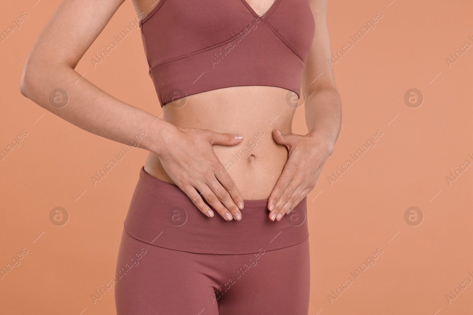 Photo of Healthy digestion. Woman touching her belly on beige background, closeup