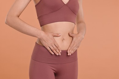 Healthy digestion. Woman touching her belly on beige background, closeup