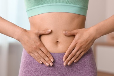 Healthy digestion. Woman touching her belly indoors, closeup