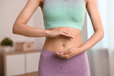 Photo of Healthy digestion. Woman holding something near her belly indoors, closeup