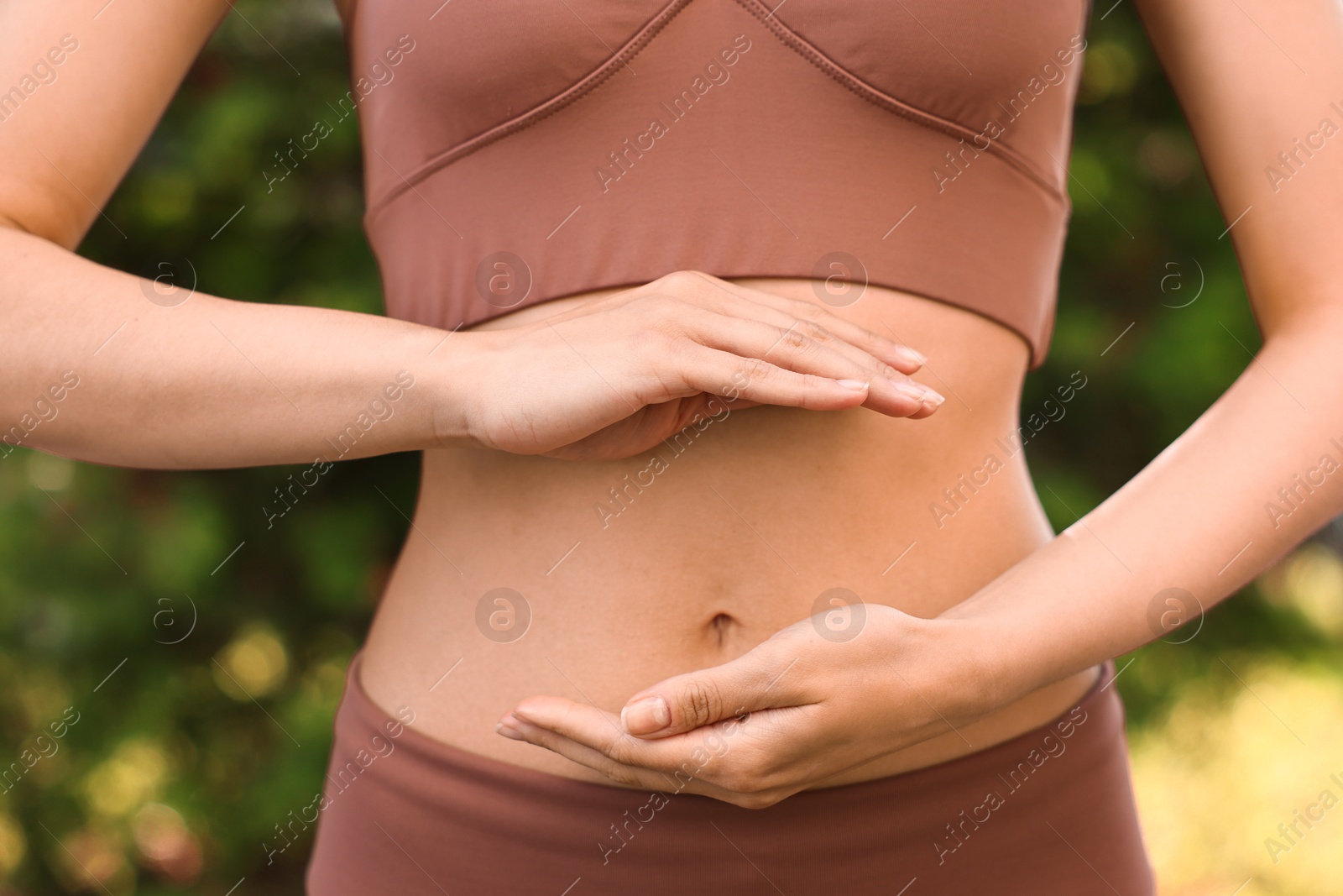 Photo of Healthy digestion. Woman holding something near her belly outdoors, closeup