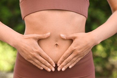 Healthy digestion. Woman touching her belly outdoors, closeup