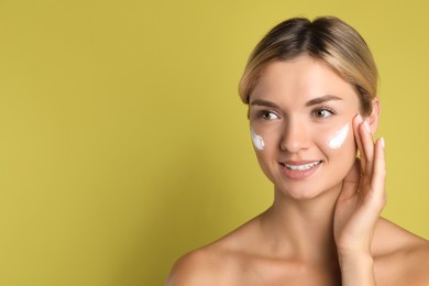 Photo of Beautiful woman with cream on her face against olive background, space for text