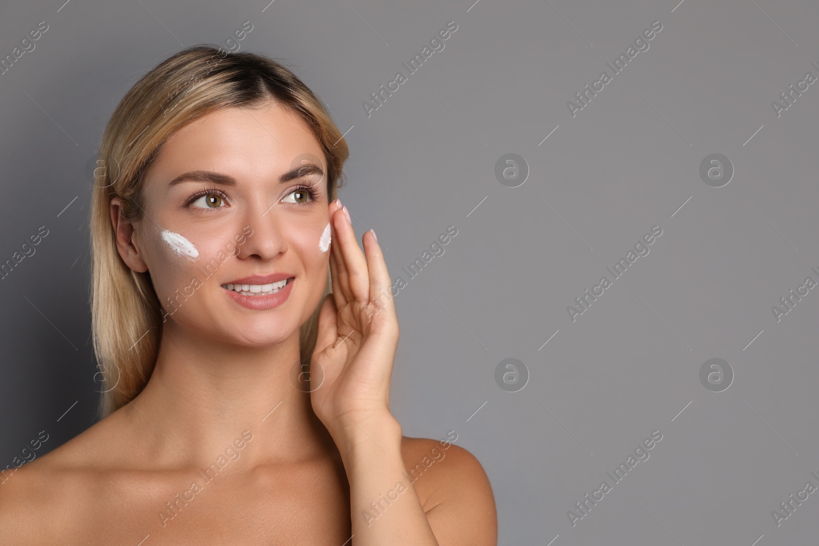 Photo of Beautiful woman with cream on her face against grey background, space for text