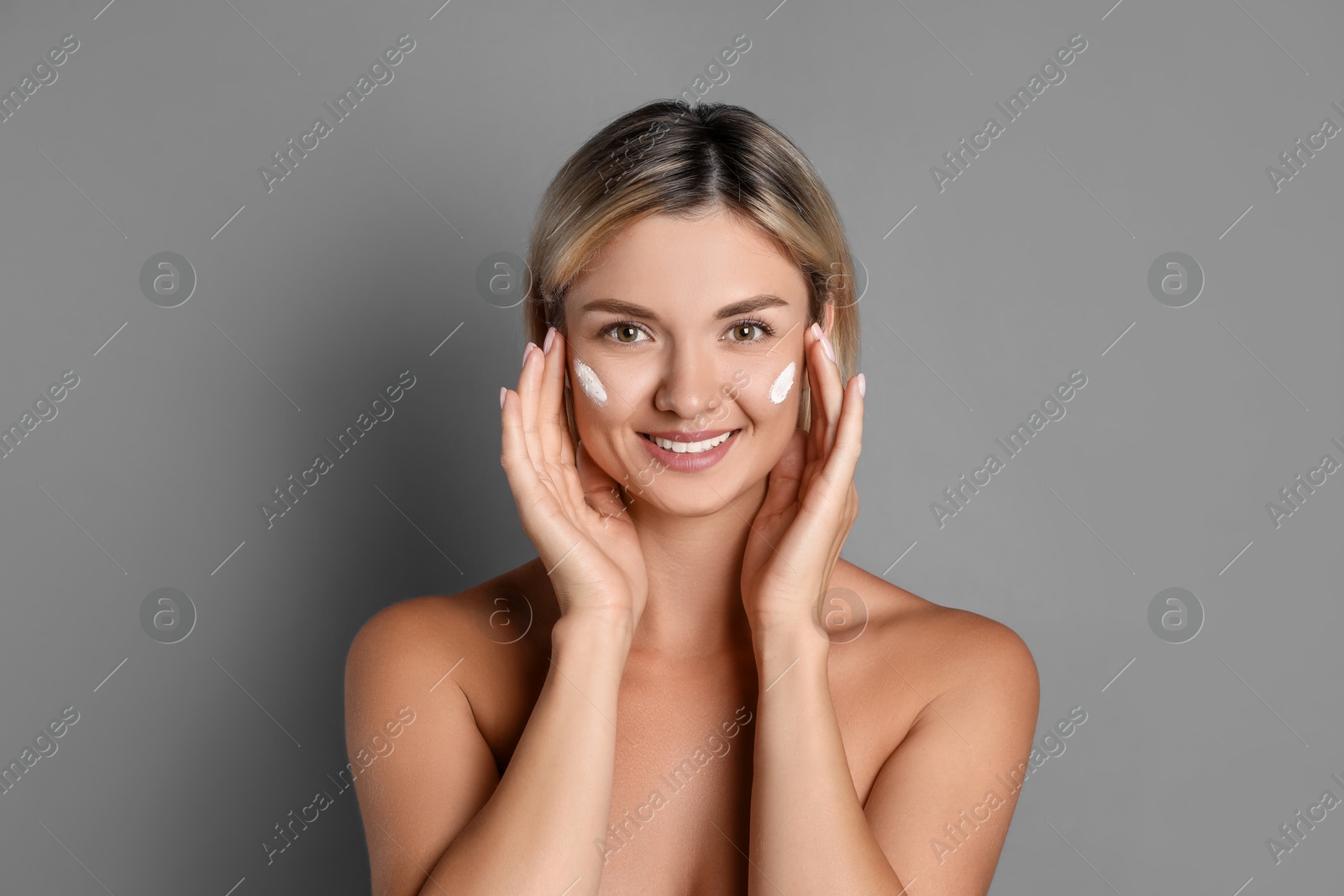 Photo of Beautiful woman with cream on her face against grey background