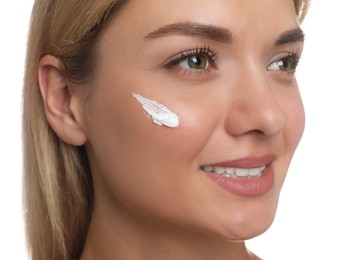 Photo of Beautiful woman with cream on her face against white background, closeup