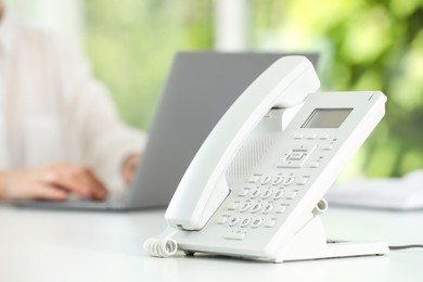 White telephone on table against blurred background, selective focus