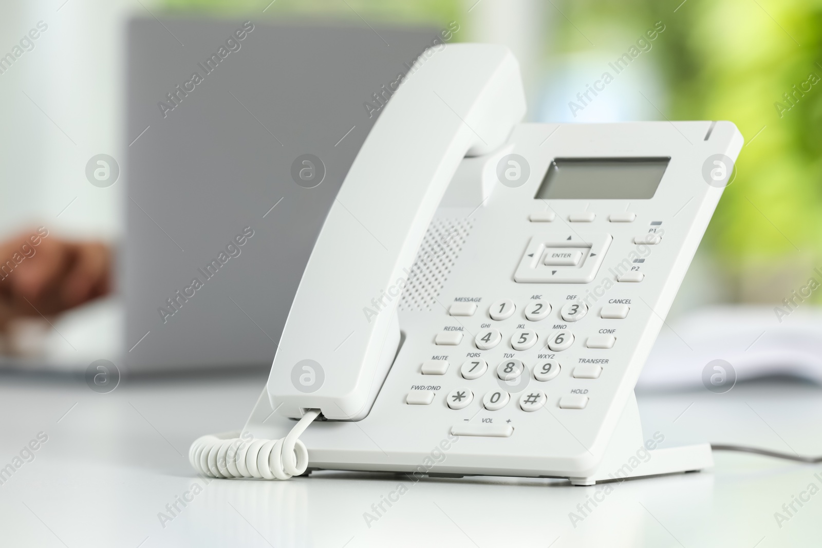 Photo of White telephone on table against blurred background, selective focus