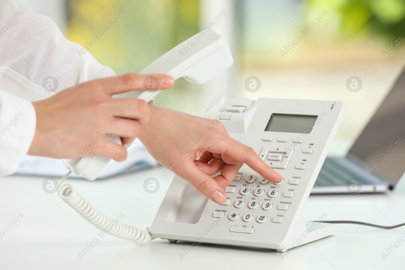 Photo of Assistant dialing number on telephone against blurred green background, closeup