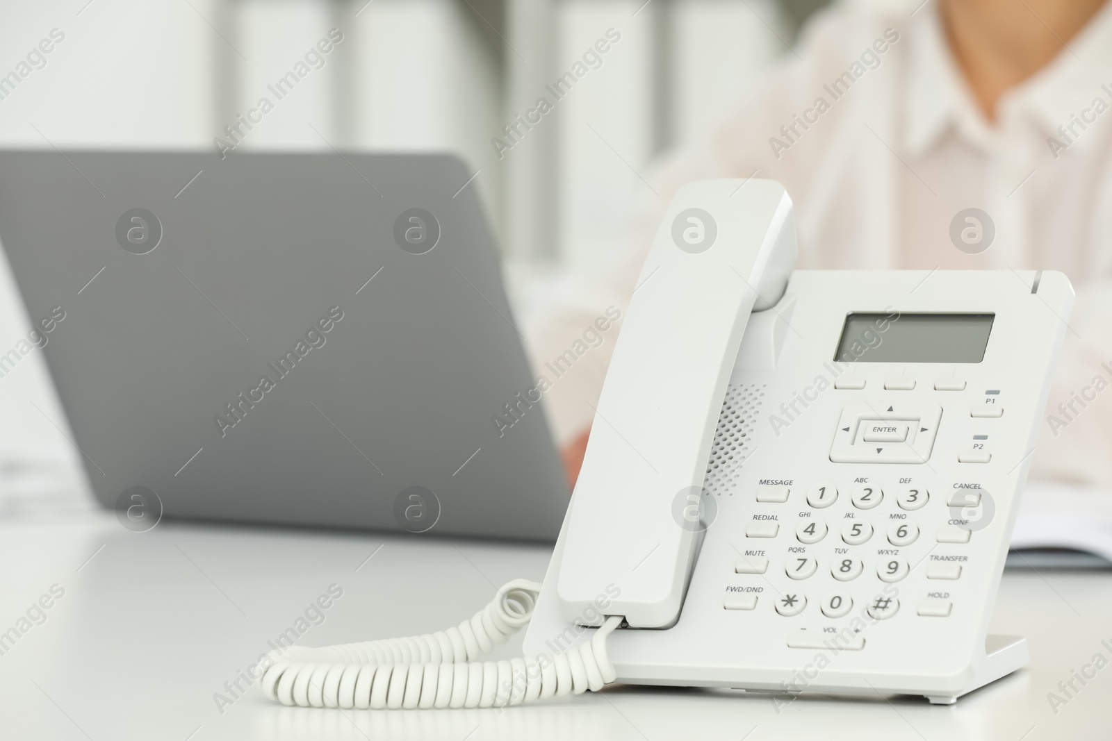 Photo of White telephone on table against blurred background, selective focus