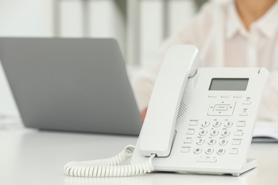 White telephone on table against blurred background, selective focus