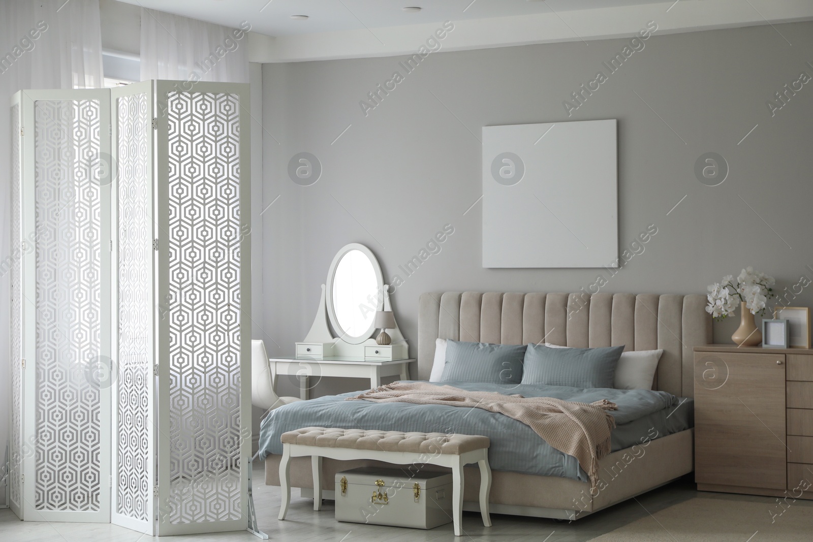 Photo of Folding screen, mirror and comfortable bed in bedroom. Interior design