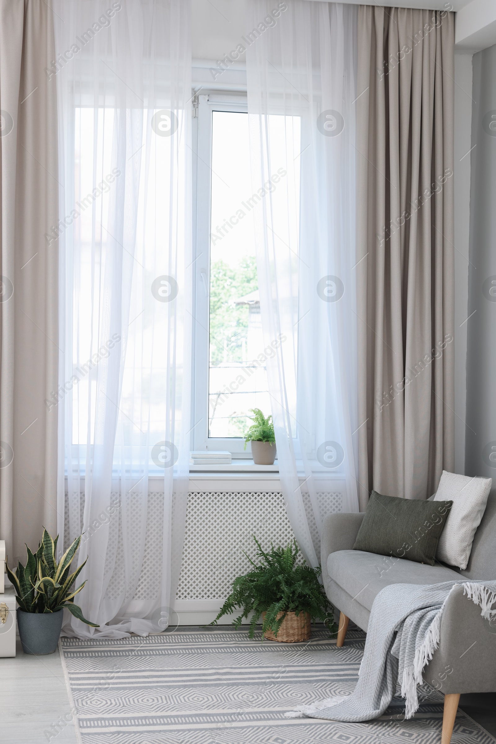 Photo of Comfortable sofa and elegant curtains in living room. Interior design