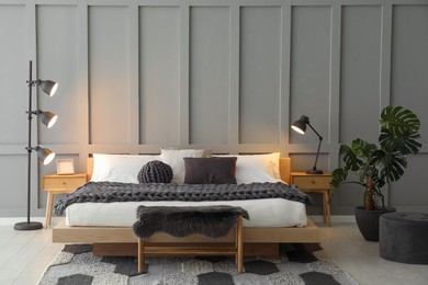 Photo of Stylish bedroom interior with comfortable bed, lamps and houseplant