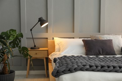 Photo of Stylish bedroom interior with comfortable bed, lamps and houseplant