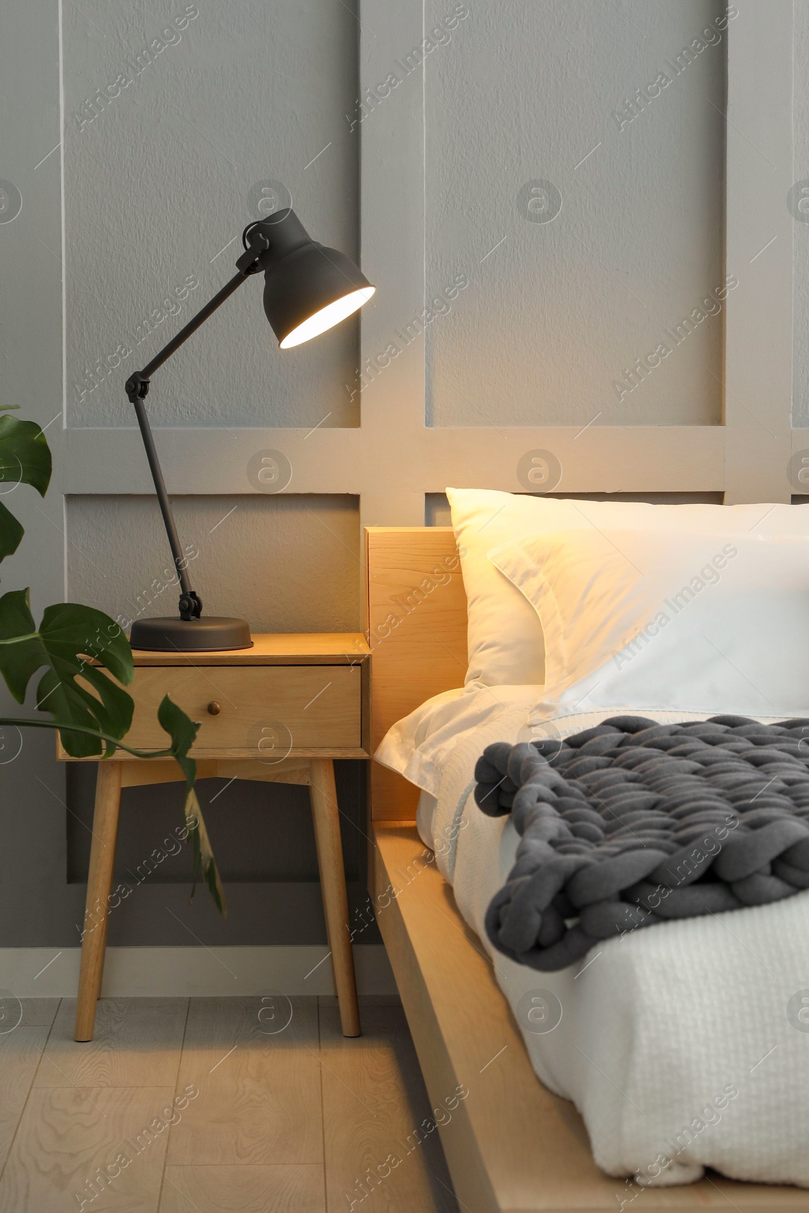 Photo of Stylish bedroom interior with comfortable bed, lamps and houseplant