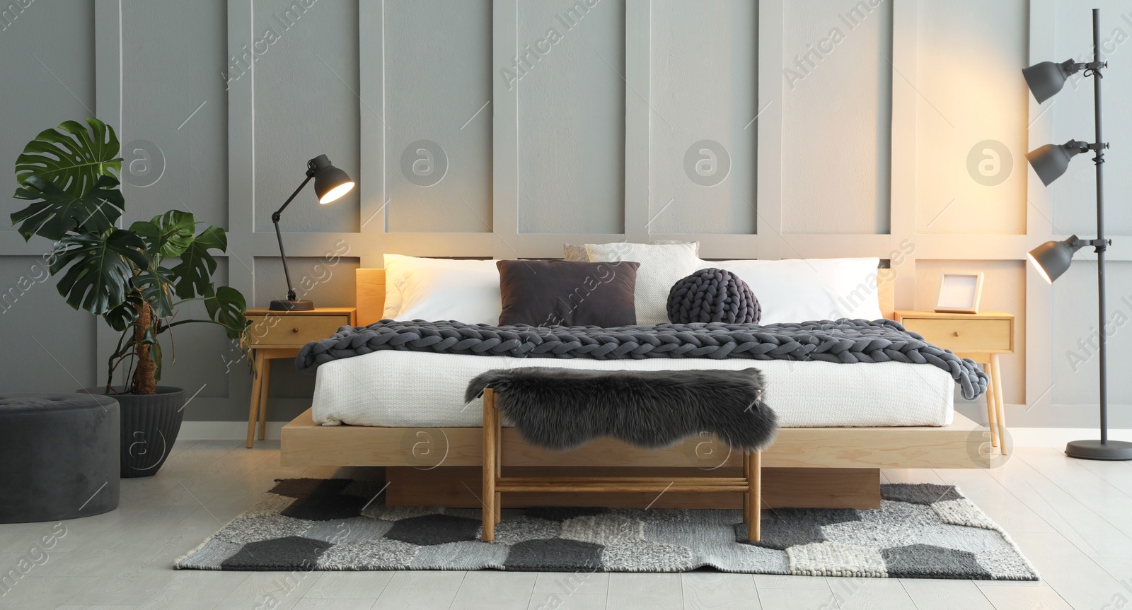 Photo of Stylish bedroom interior with comfortable bed, lamps and houseplant