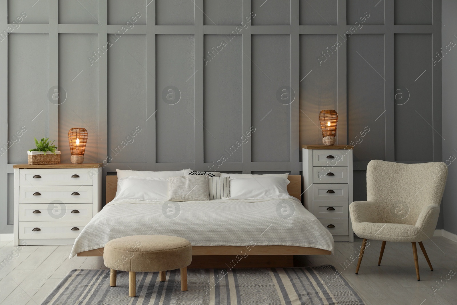 Photo of Stylish bedroom interior with comfortable bed, lamps, armchair and houseplant