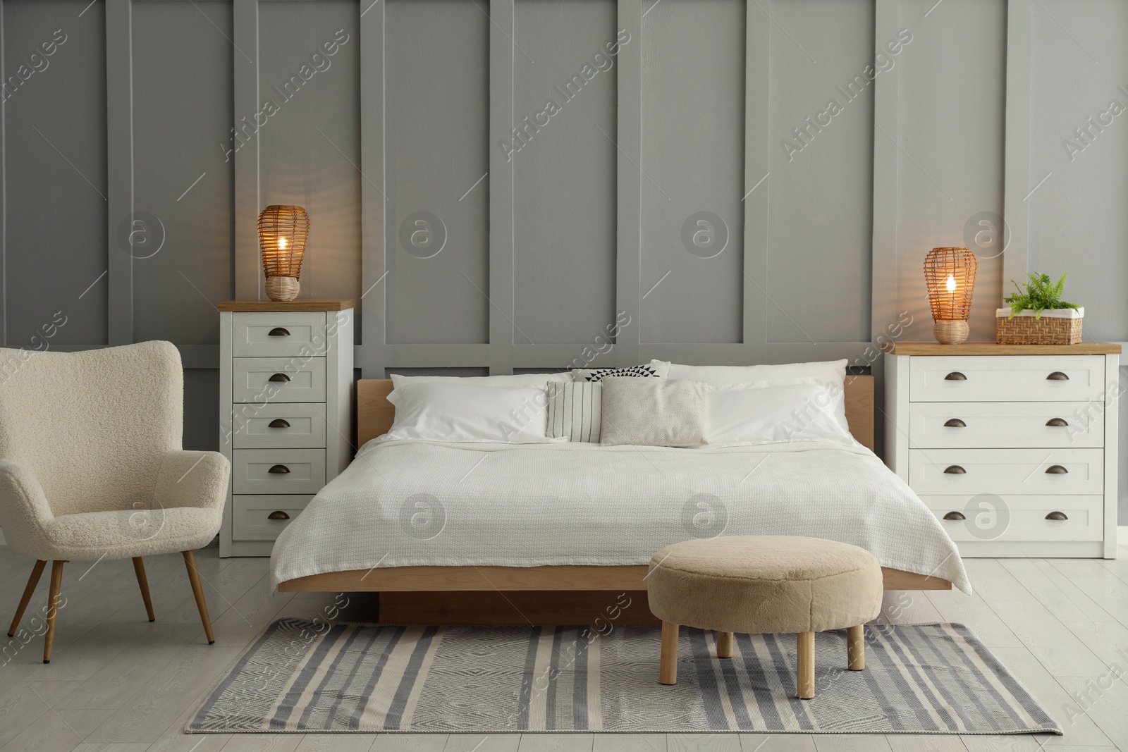 Photo of Stylish bedroom interior with comfortable bed, lamps, armchair and houseplant