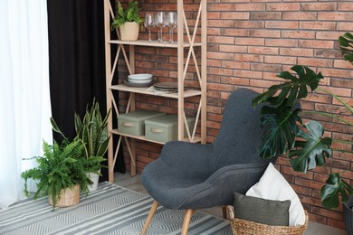 Photo of Shelving unit, green houseplants, armchair, pillows and elegant curtain in room. Interior design