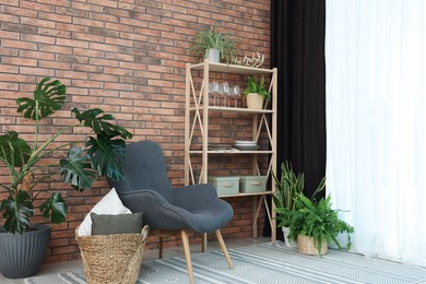 Photo of Shelving unit, green houseplants, armchair, pillows and elegant curtain in room. Interior design