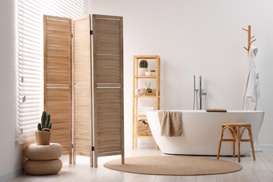 Wooden folding screen, bathtub, chair and rack in bathroom