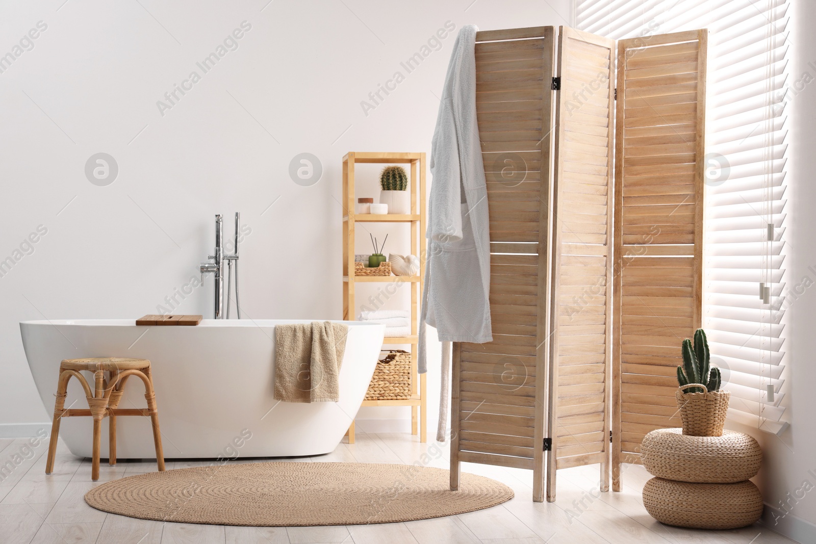 Photo of Wooden folding screen, bathtub, chair and rack in bathroom