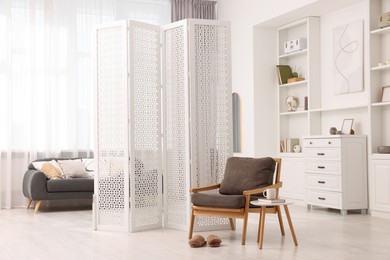 White folding screen, armchair and wooden table in living room