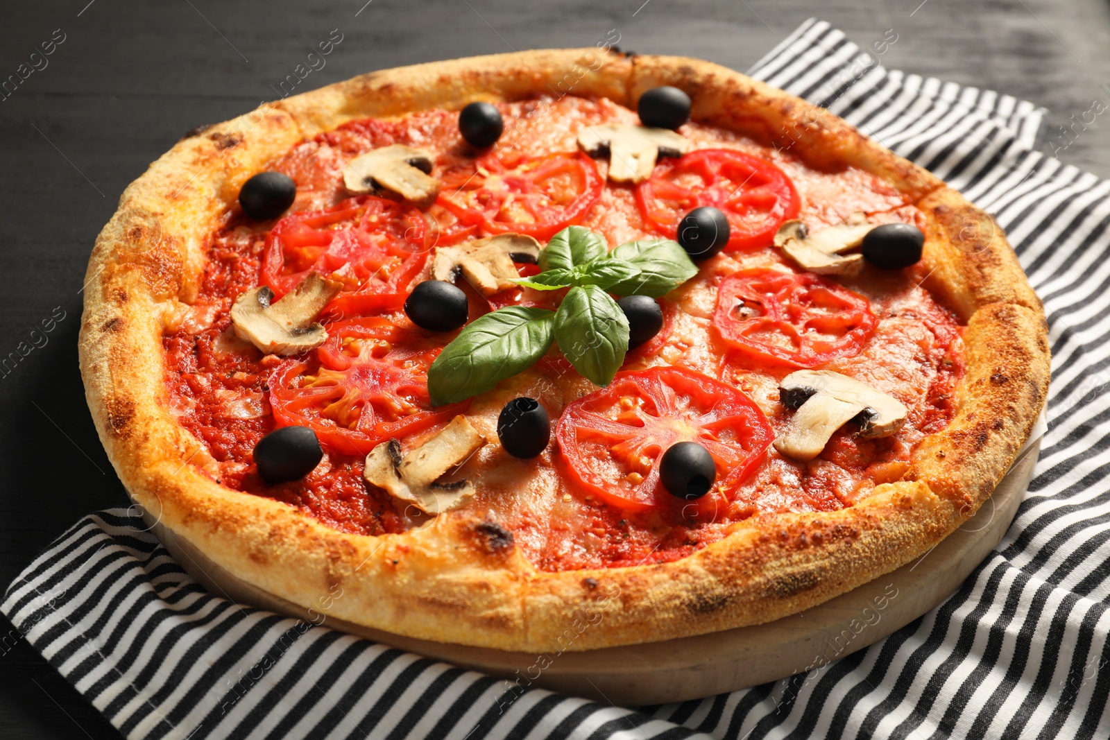 Photo of Delicious pizza with tomatoes, mushrooms, olives and basil on black table, closeup