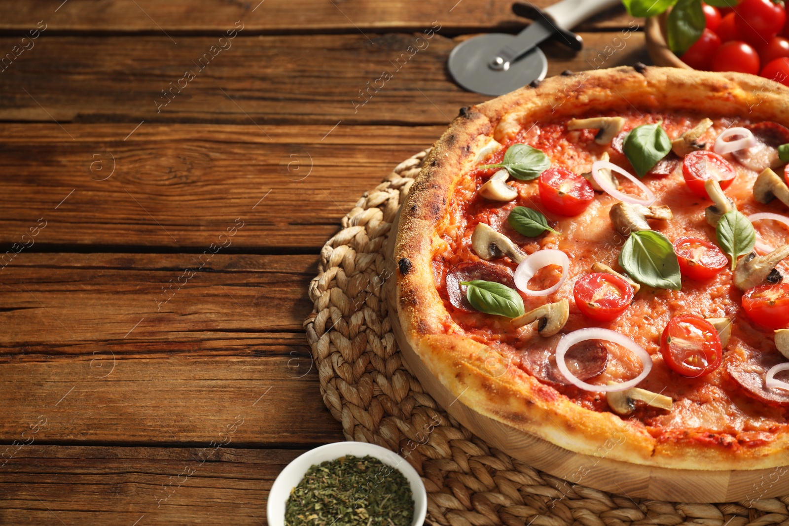 Photo of Delicious pizza with salami, vegetables, mushrooms and basil on wooden table, closeup. Space for text