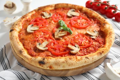 Delicious pizza with tomatoes, mushrooms and basil on table, closeup