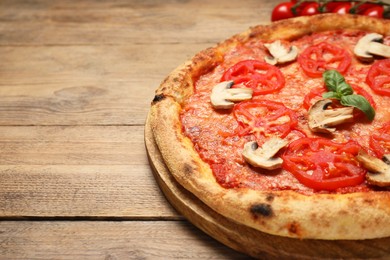 Photo of Delicious pizza with tomatoes, mushrooms and basil on wooden table, closeup. Space for text