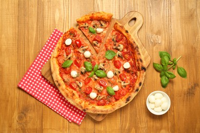 Photo of Tasty pizza with basil, mushrooms, mozzarella and tomato on wooden table, flat lay