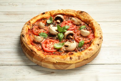 Photo of Tasty pizza with basil, mushrooms and tomato on wooden rustic table