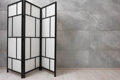 Photo of Stylish folding screen near grey wall indoors, space for text. Interior element