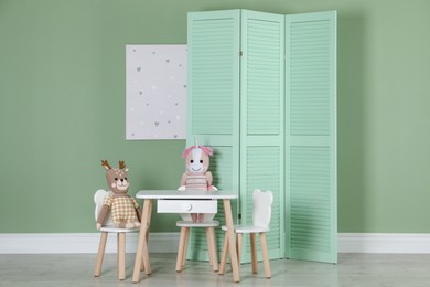 Folding screen, small chairs, table, toys and picture indoors