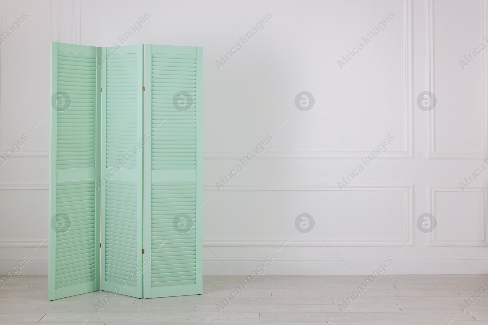 Photo of One folding screen near white wall indoors, space for text. Interior element