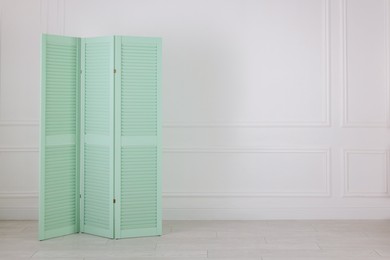 Photo of One folding screen near white wall indoors, space for text. Interior element