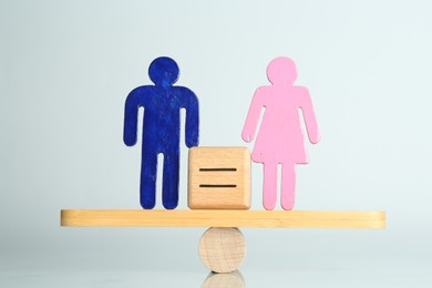 Photo of Gender equality concept. Male and female figures on scales against light background