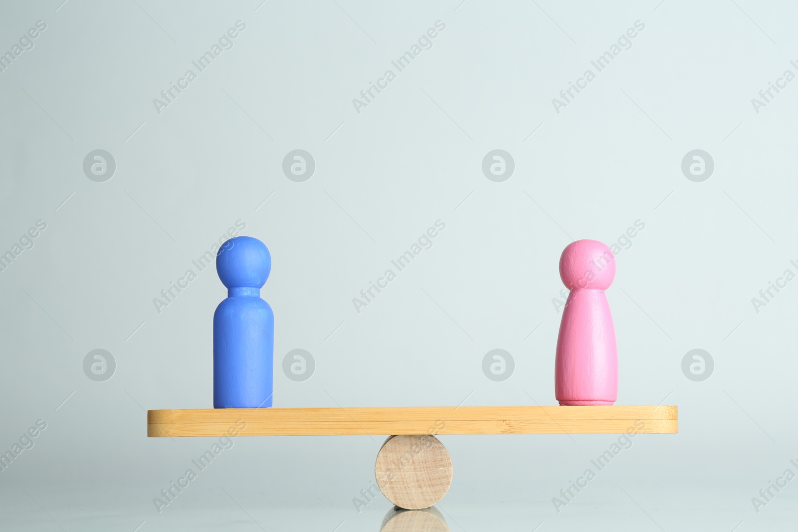 Photo of Gender equality concept. Male and female figures on scales against light background