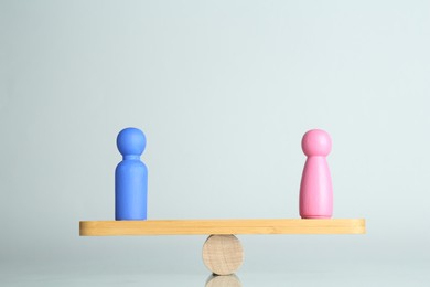 Photo of Gender equality concept. Male and female figures on scales against light background