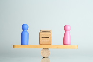 Photo of Gender equality concept. Male and female figures on scales against light background