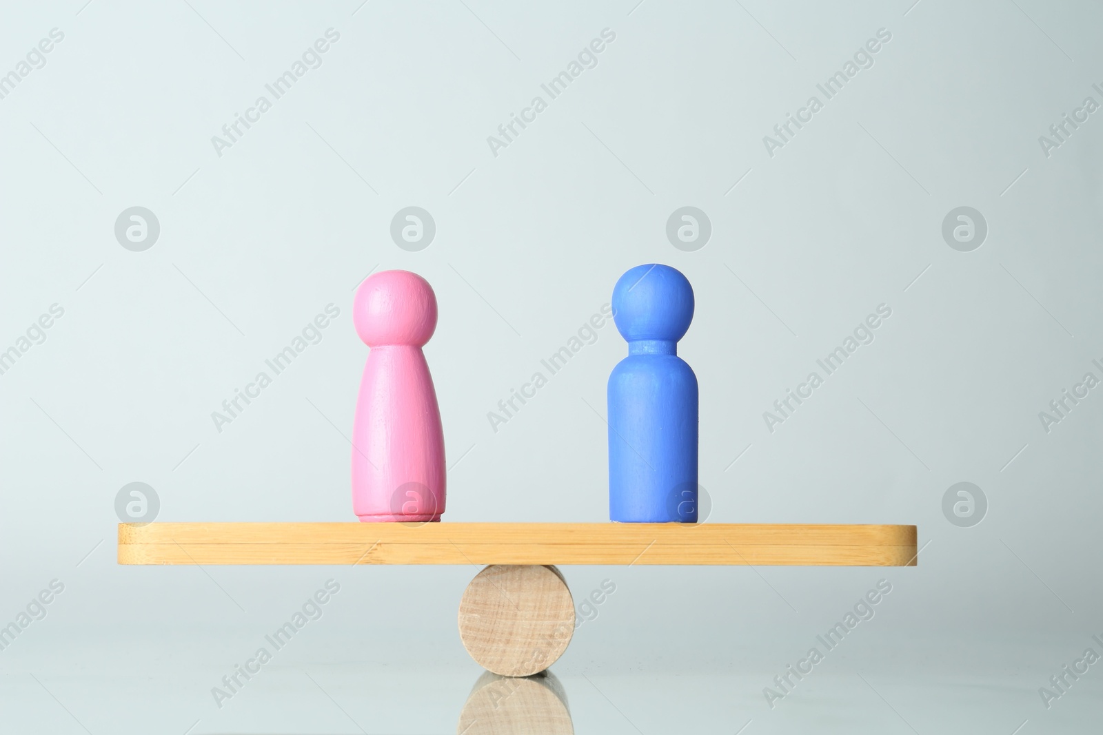 Photo of Gender equality concept. Male and female figures on scales against light background