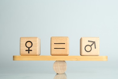 Photo of Gender equality concept. Cubes with male and female symbols on scales against light background