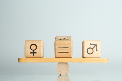 Photo of Gender equality concept. Cubes with male and female symbols on scales against light background