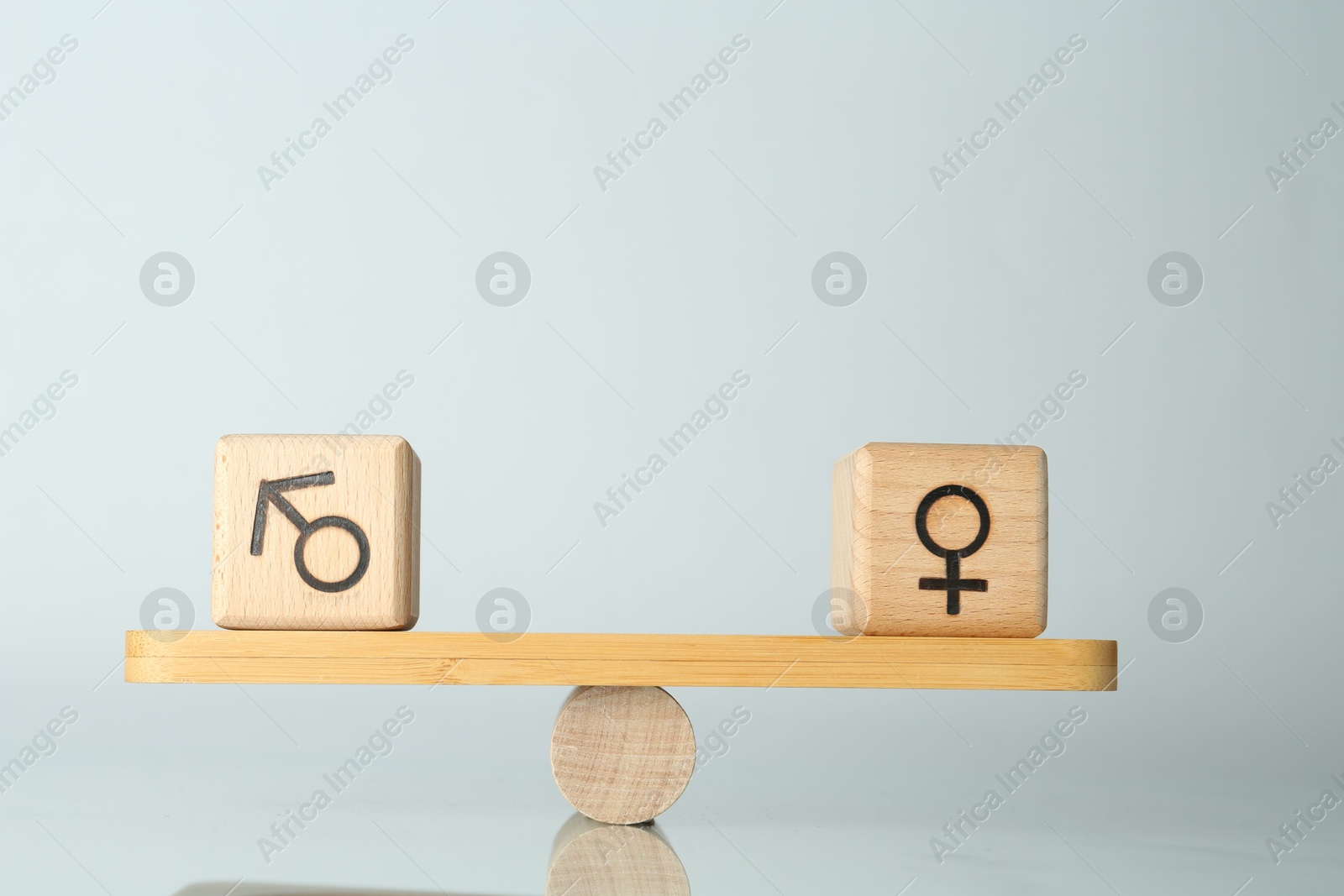 Photo of Gender equality concept. Cubes with male and female symbols on scales against light background