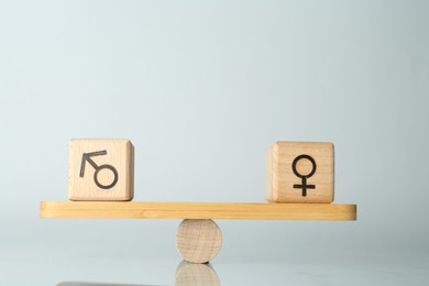 Photo of Gender equality concept. Cubes with male and female symbols on scales against light background