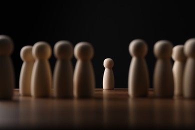 Photo of Loneliness concept. Human figure alone among others on wooden table